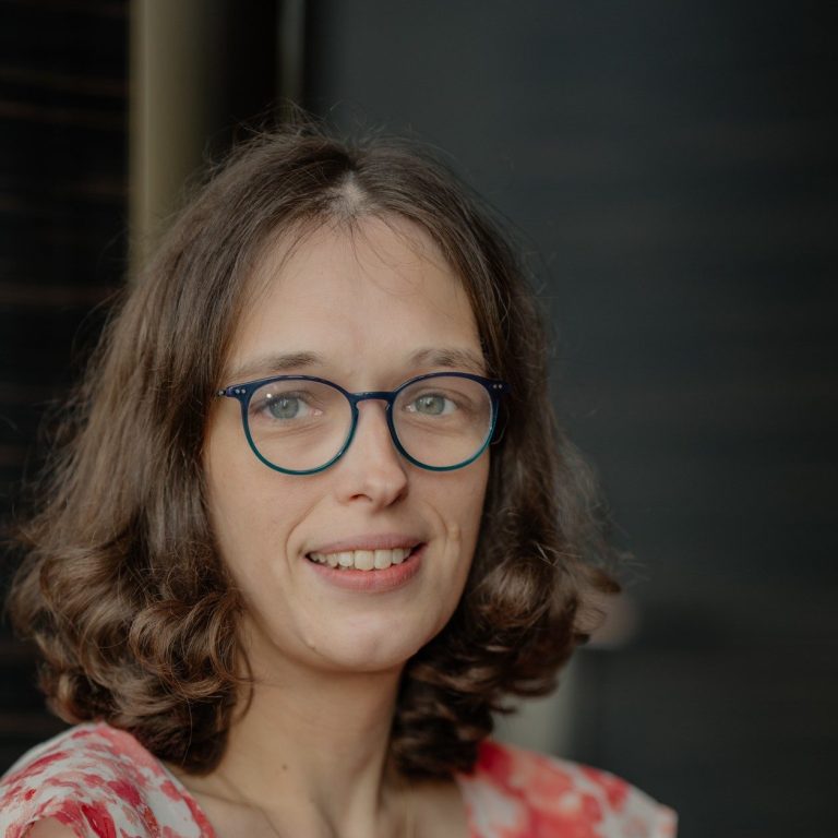 Copywriterin Monika Schmitt Das Bild zeigt das Gesicht von Monika. Sie hat halblange dunkelblonde Haare und trägt eine Brille.